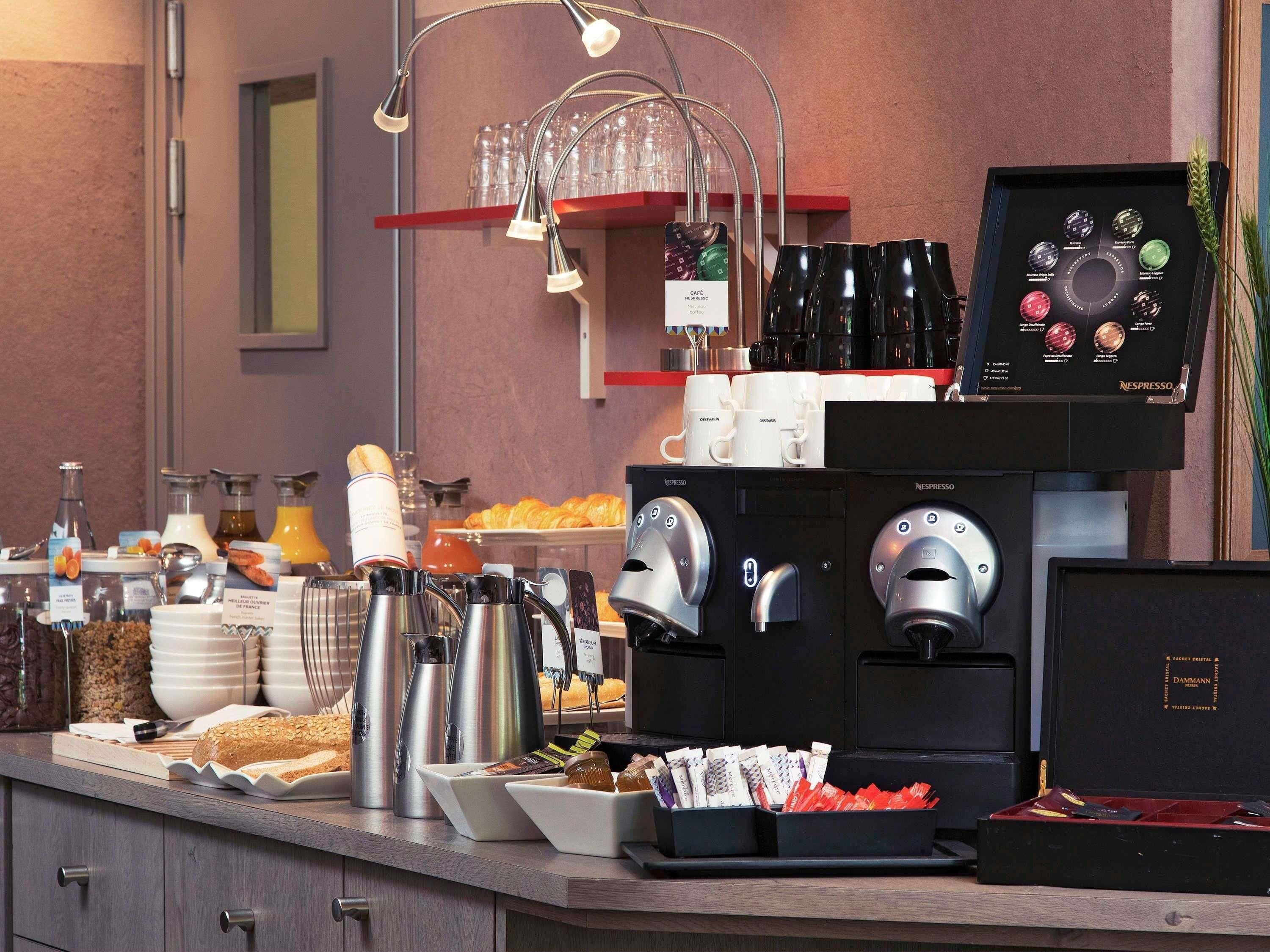 A breakfast buffet with coffee machines, pastries, and beverages.