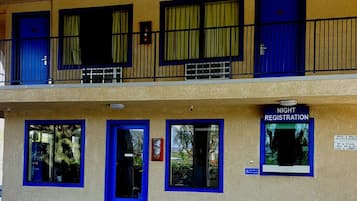 A building with a registration sign for night registration, multiple doors, and windows with curtains.