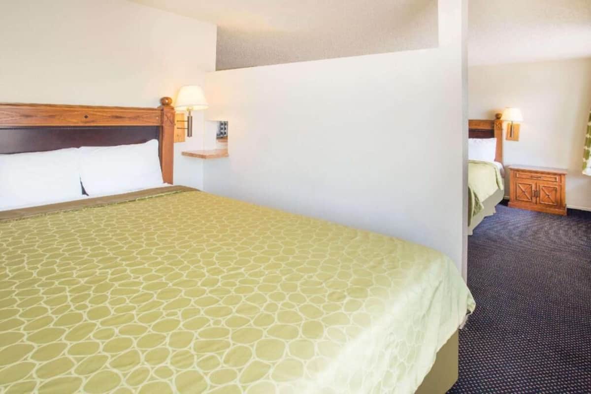 A hotel room with a large bed, a nightstand with a lamp, and a small cabinet.