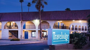 Un hotel Travelodge con techo de tejas rojas, ventanas arqueadas y un cartel.