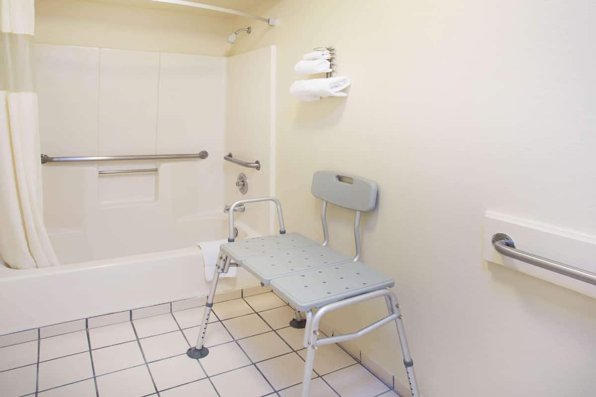 A bathroom with a bathtub, a shower, a toilet, and a grab bar.