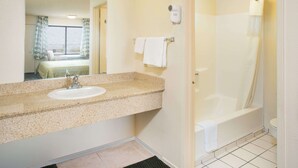 Un baño con lavabo, espejo, toallero y zona de ducha.