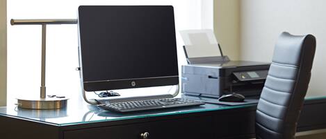 Un escritorio moderno con una computadora de escritorio, una impresora y una silla.