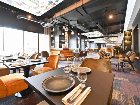A restaurant with tables set for dining, a bar area, and a staircase leading to an upper level.