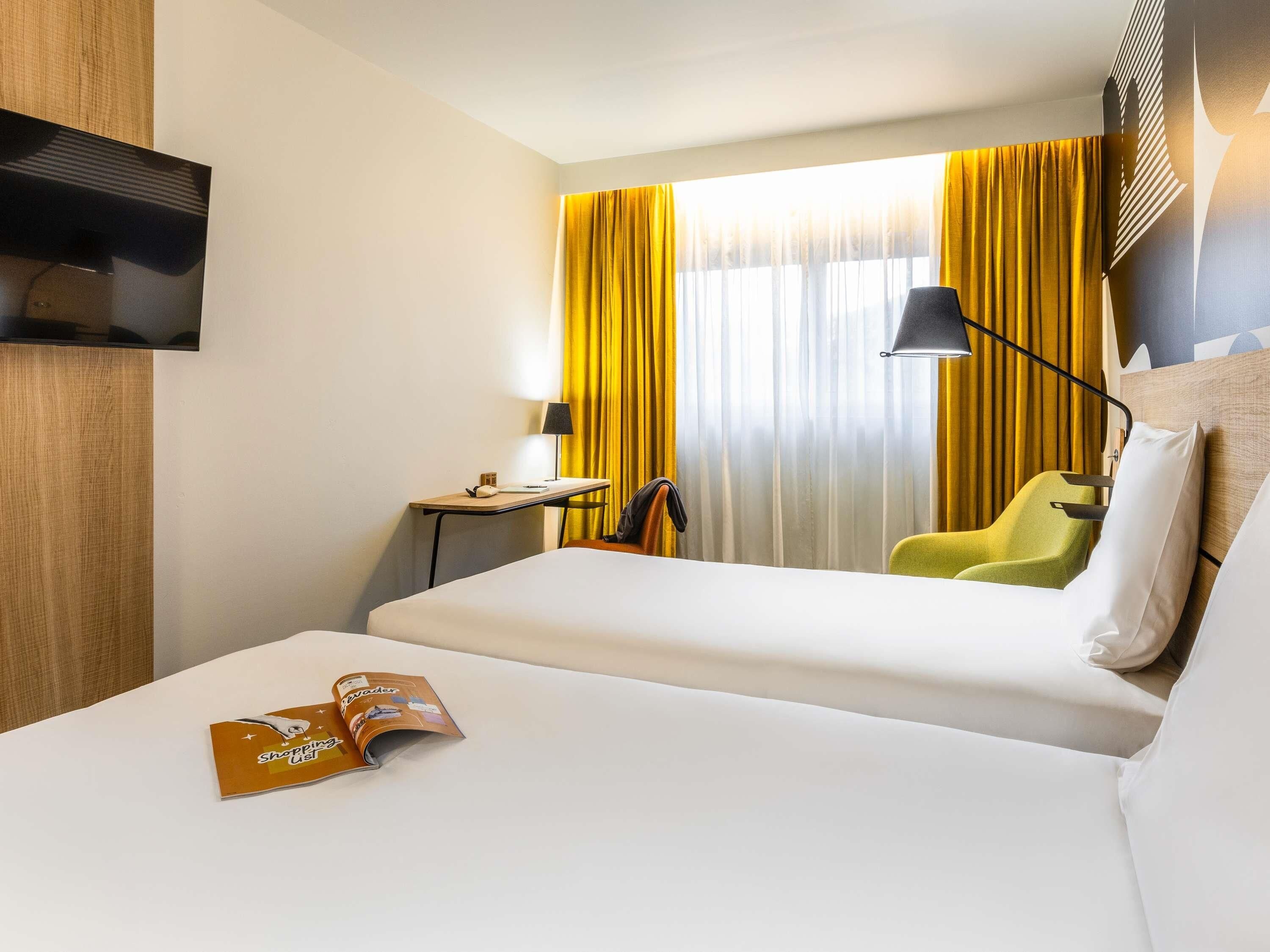 Une chambre d’hôtel avec un lit, un bureau, une chaise et un téléviseur.