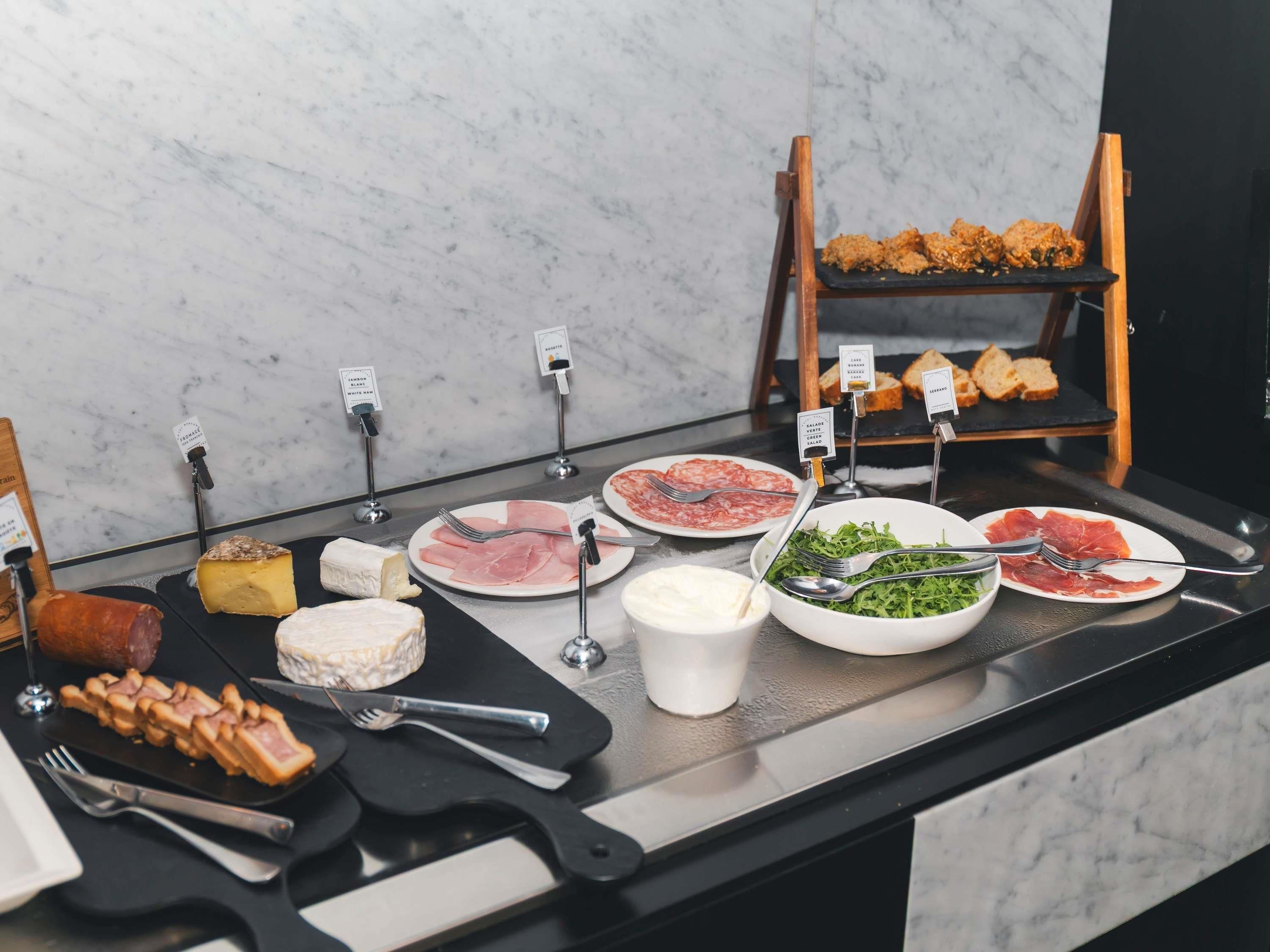 Un bufé con diversos alimentos, incluyendo carnes, quesos y ensaladas.