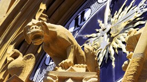 Escultura arquitectónica detallada con una figura de león y una esfera de reloj.