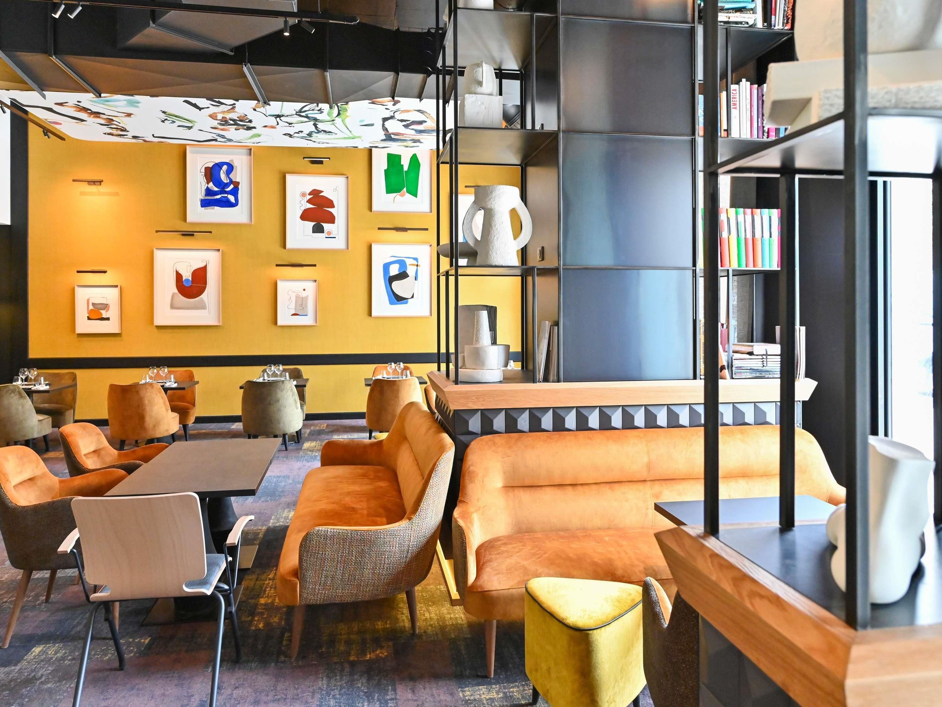 Een modern interieur met een bank, stoelen, tafels en kunstwerken aan de muren.