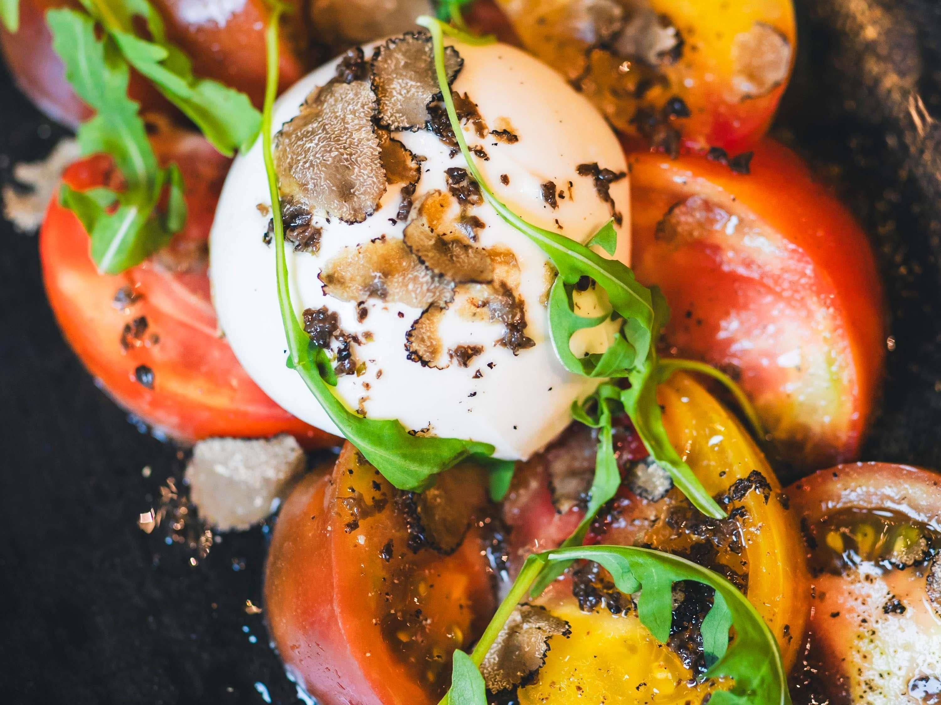 A close-up of a dish with a poached egg, tomatoes, and greens.