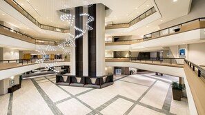 A multi-level atrium with a central column, multiple floors, and a modern chandelier.