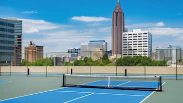 An outdoor tennis court with a city skyline in the background.