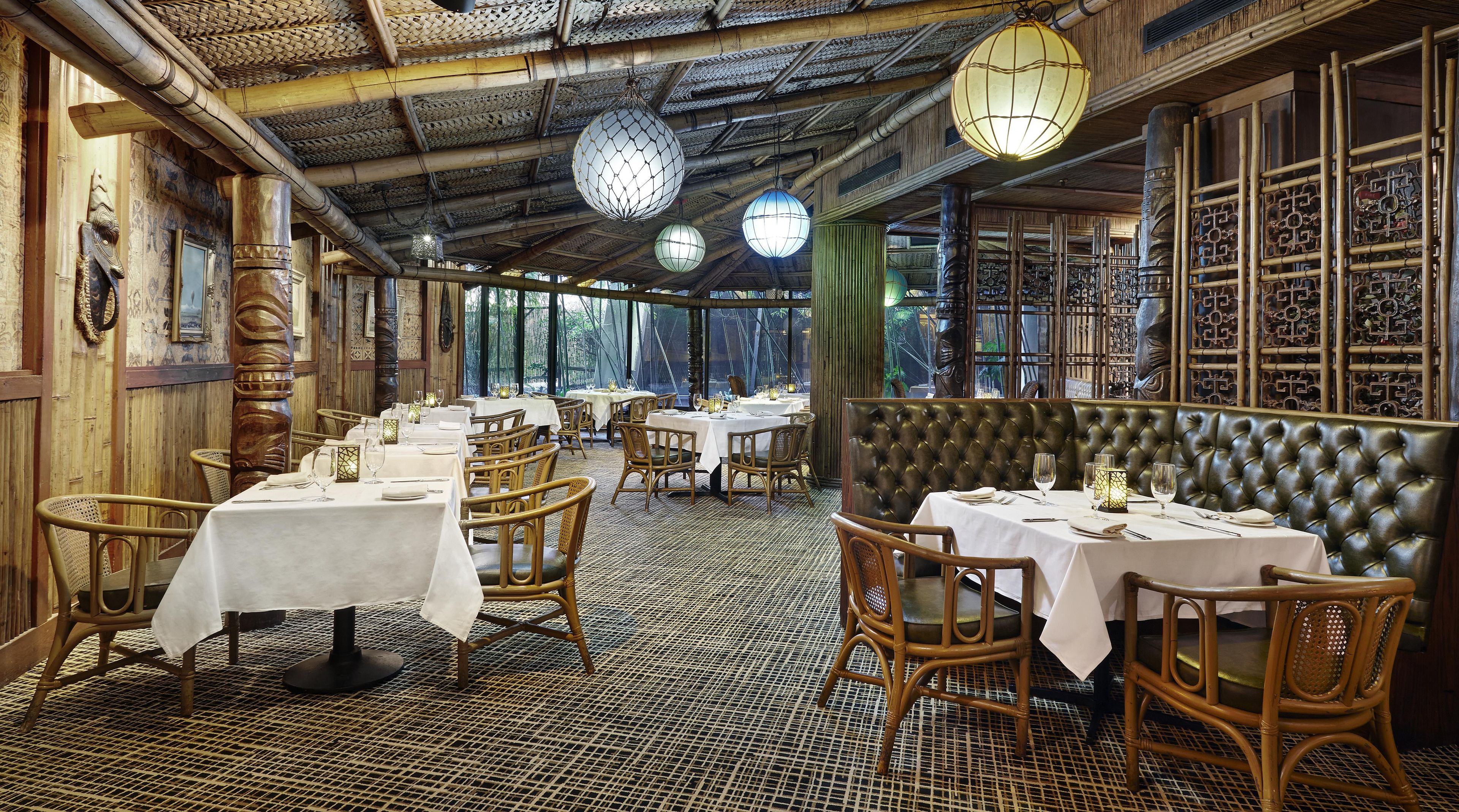A restaurant with round tables, wicker chairs, and a patterned floor.