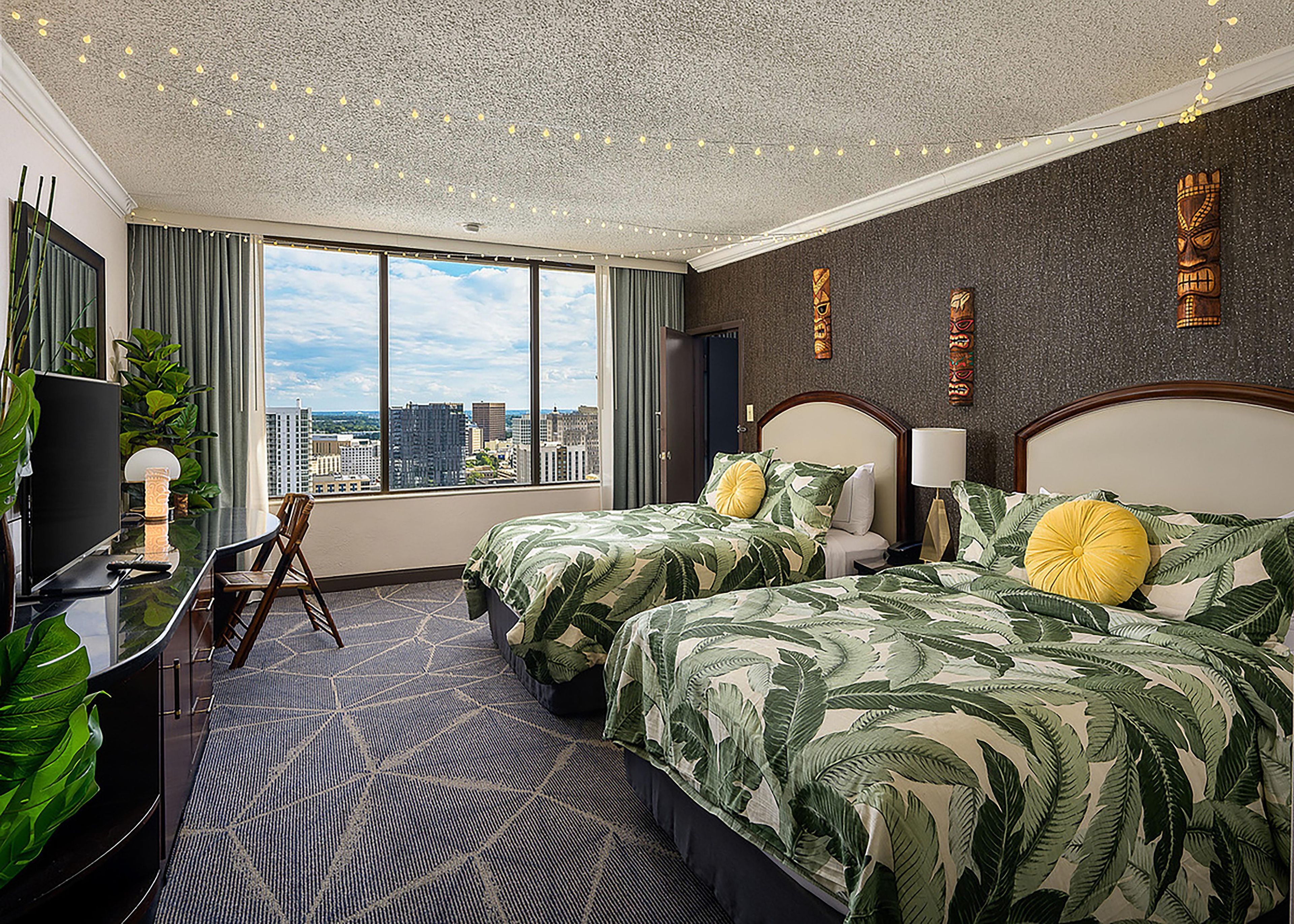 Una habitación de hotel con dos camas, un escritorio y vistas a la ciudad.