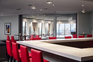 A modern hotel lobby with a large central island, red chairs, and a view of the cityscape through large windows. - Hilton Atlanta (Atlanta)