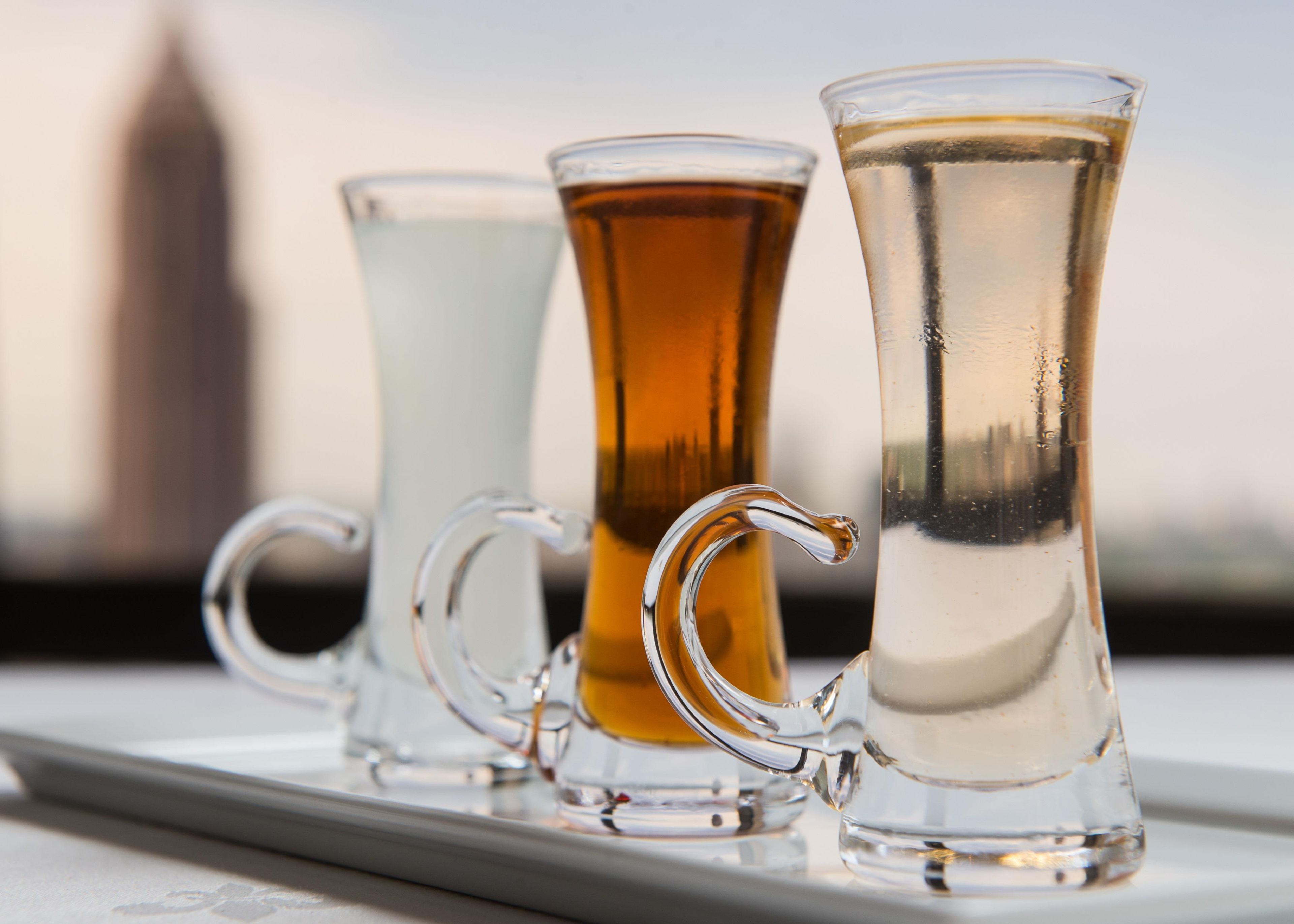 Three glass mugs with handles on a table.