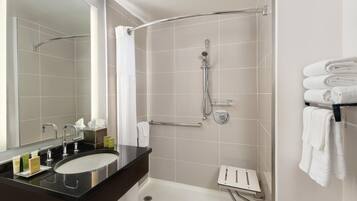 A modern bathroom with a curved shower, a vanity with a sink, and a towel rack.