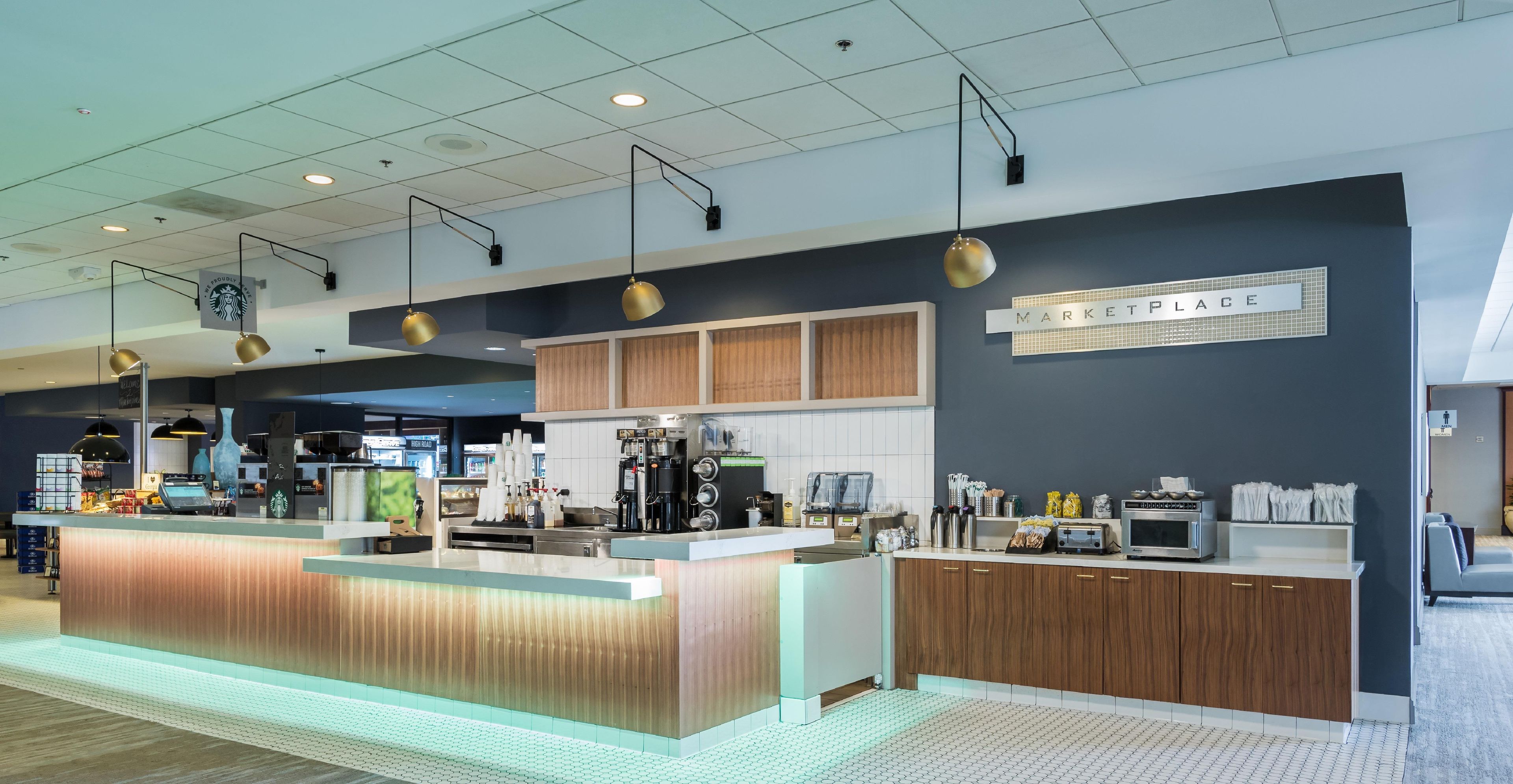 L’intérieur d’un café moderne, avec un comptoir, des machines à expresso et un panneau indiquant un marché.