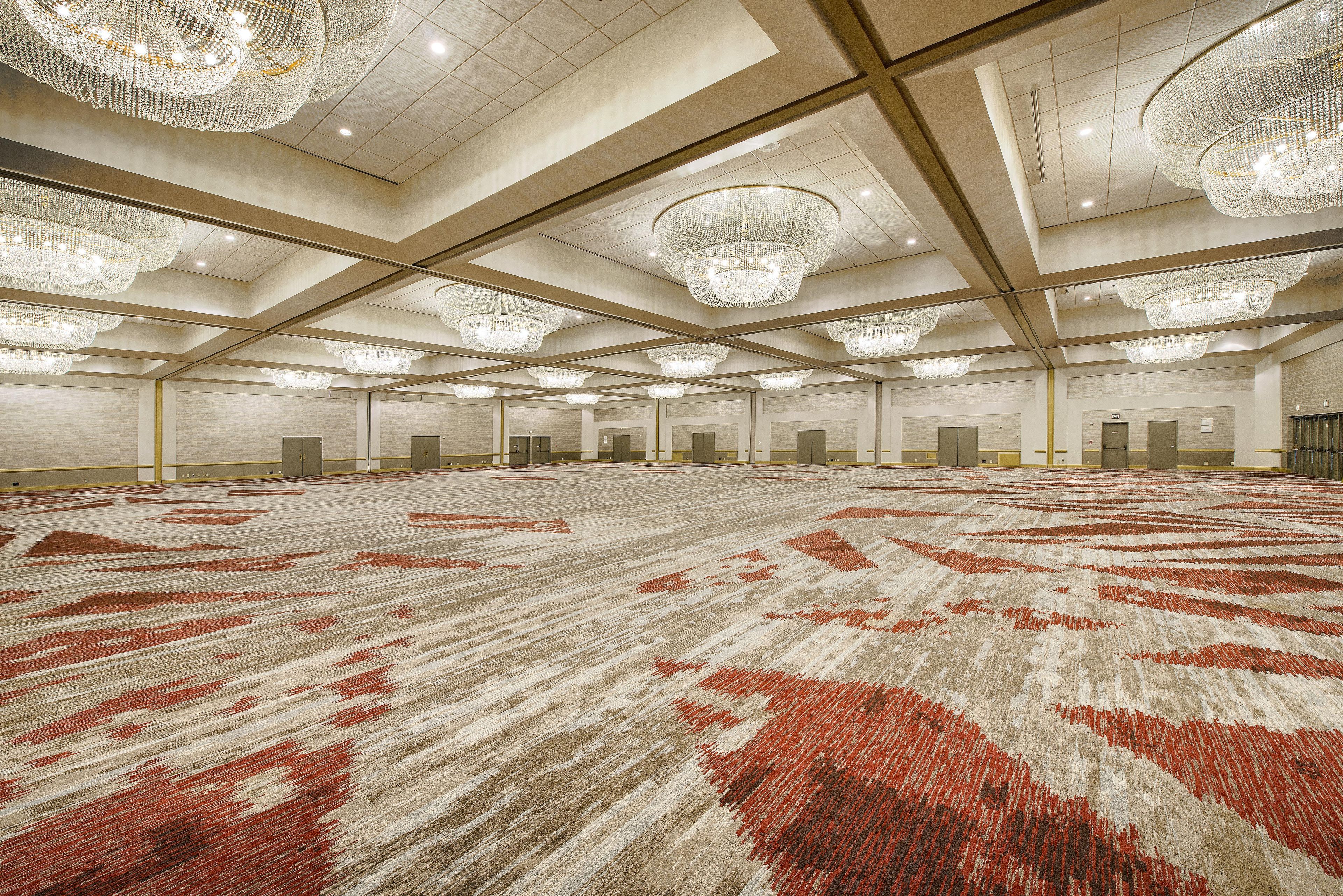 A large, well-lit conference room with multiple chandeliers and a patterned carpet.