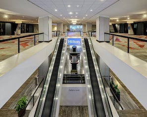 An interior view of a hotel lobby with an escalator leading to the Galleria Level, featuring a prominent Hilton sign. - Hilton Atlanta (Atlanta)