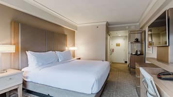 Habitación de hotel con cama, mesita de noche, lámpara, escritorio, silla y espejo.