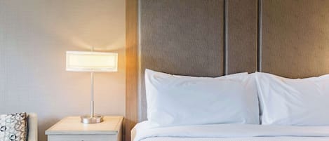 A hotel room with a bed, a bedside table with a lamp, and a nightstand.