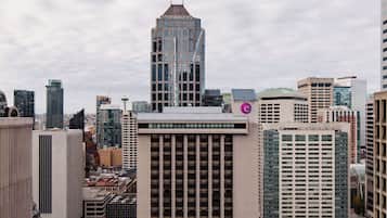 A cityscape with high-rise buildings, including a prominent glass skyscraper with a unique top.