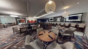 A hotel lobby with a bar area, seating arrangements, and a television screen. - Coast Seattle Downtown Hotel by APA (Seattle)