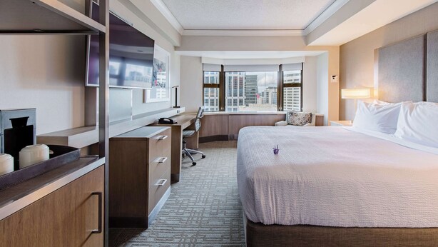 A hotel room with a large bed, a desk with a chair, a TV, and a window with a city view. - Coast Seattle Downtown Hotel by APA (Seattle)