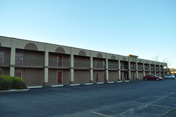 A multi-story motel with a row of rooms, a parking lot, and a few cars parked. - Best Way Inn Madison (Madison)