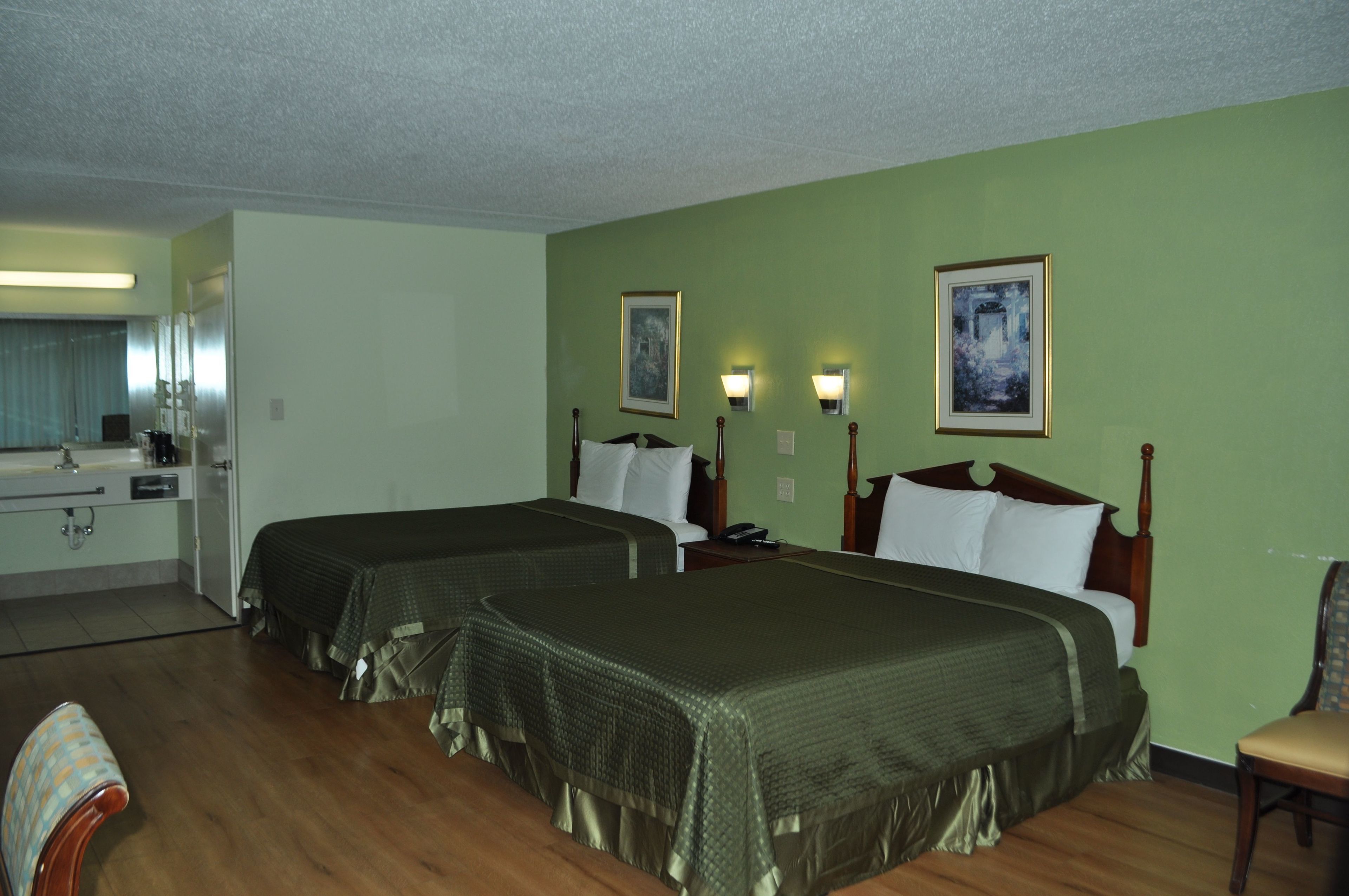 Ein Hotelzimmer mit zwei Betten, einem Schreibtisch, einem Stuhl und einem Badezimmer.