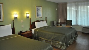 Ein Hotelzimmer mit zwei Betten, einem Nachttisch mit Telefon, einem Sessel und einem Fenster mit Vorhängen.