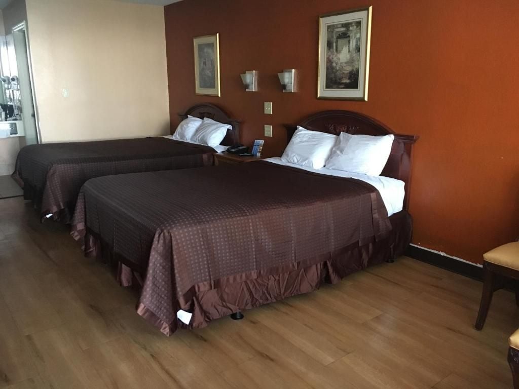 Une chambre d’hôtel avec deux lits, un plancher en bois et des œuvres d’art accrochées aux murs.