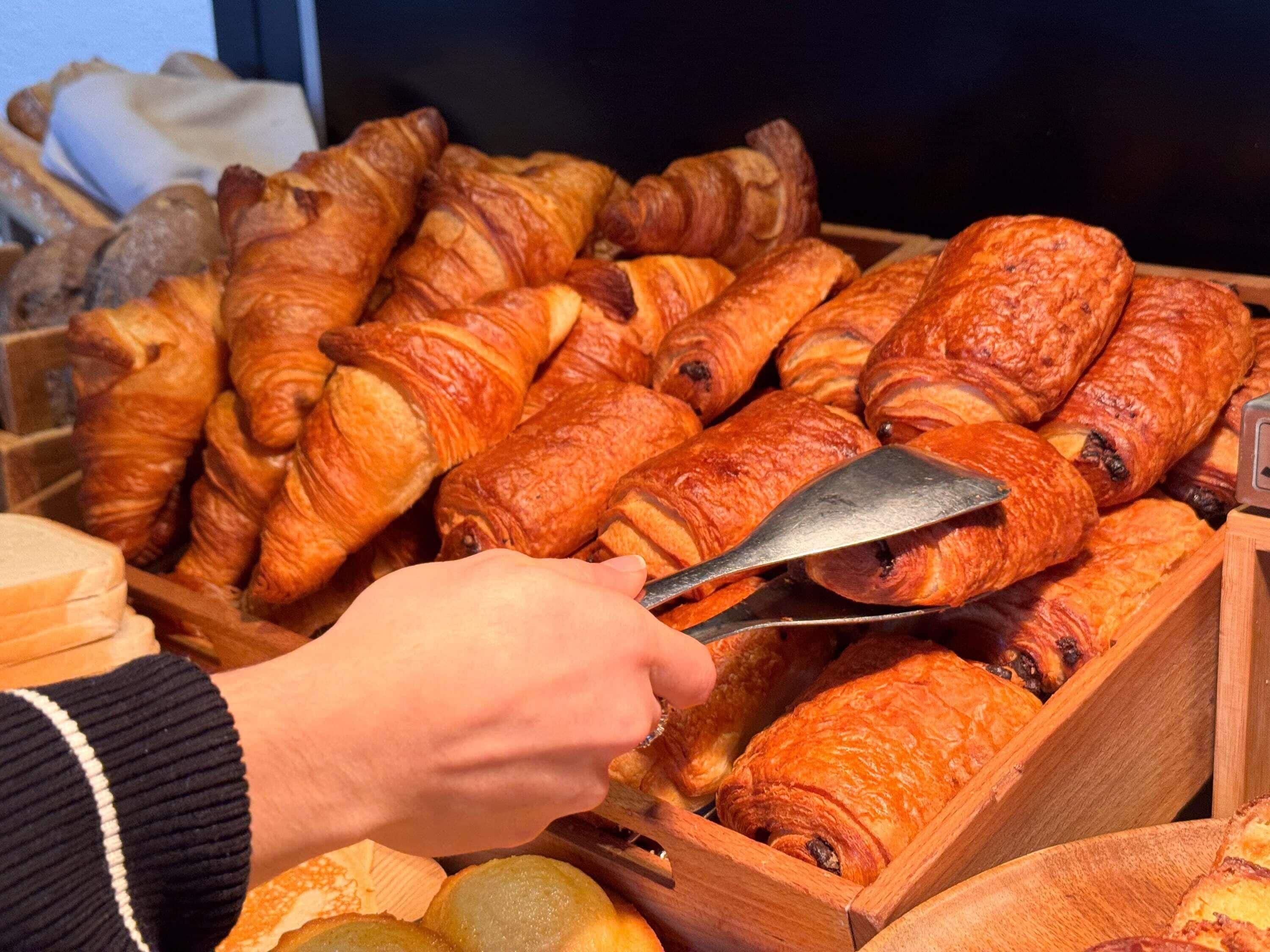 A variety of baked goods, including croissants and bread, displayed in wooden trays.