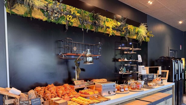 A breakfast buffet with various pastries and bread, a coffee station, and a vertical garden on the wall. - ibis Ales Centre Ville Hotel (Ales)