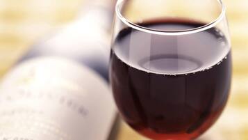 Una copa de vino tinto con una botella desenfocada al fondo.