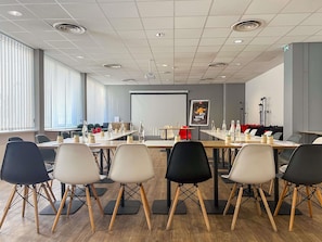 A conference room with a long table, chairs, a projector screen, and a whiteboard.