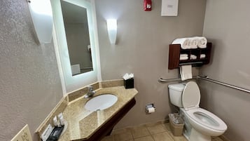 A bathroom with a sink, mirror, toilet, and towel rack.