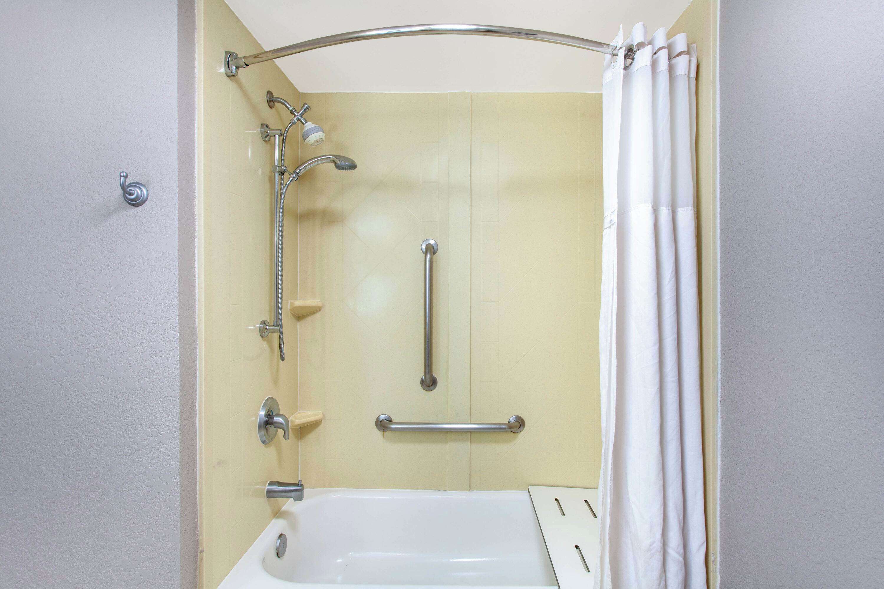 A bathroom with a shower, grab bars, and a bathtub.