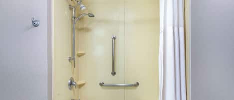 A bathroom with a shower, grab bars, and a bathtub.