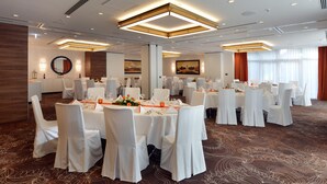 A banquet hall with round tables, white chairs, and a carpeted floor. - Best Western Plus Delta Park Hotel (Mannheim)