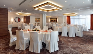 A banquet hall with round tables, white chairs, and a carpeted floor. - Best Western Plus Delta Park Hotel (Mannheim)