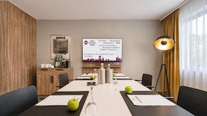 A conference room with a long table, chairs, a projector screen displaying a welcome message, and a lamp. - Best Western Plus Delta Park Hotel (Mannheim)