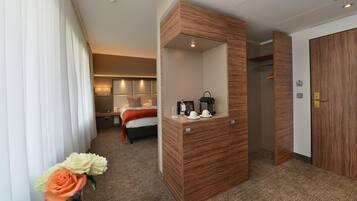 A hotel room with a bed, bedside table, mirror, and a wooden wardrobe.