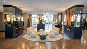 A hotel lobby with a central seating area, a reception desk, and a fireplace. - Best Western Plus Delta Park Hotel (Mannheim)