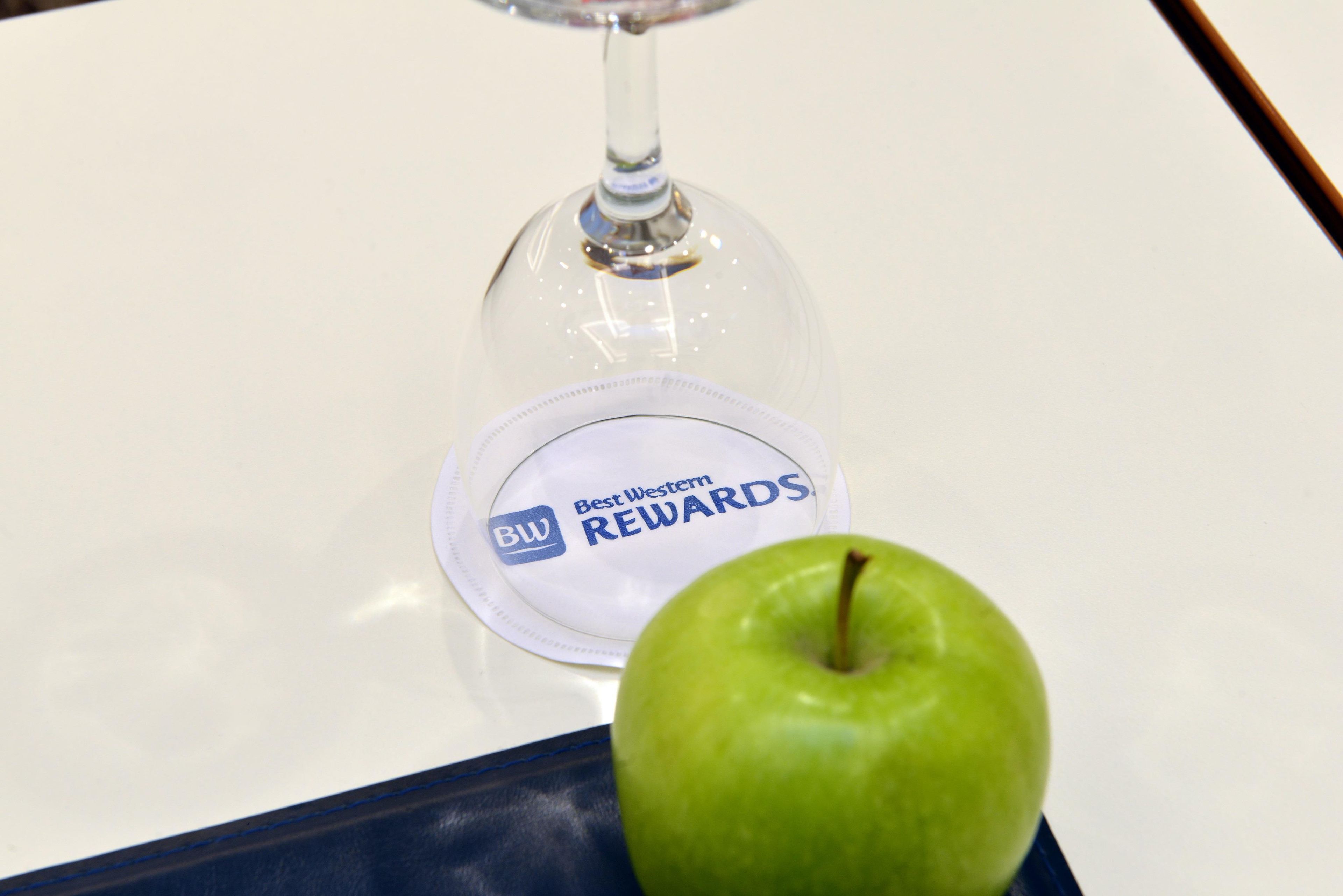 Une cloche de verre sur laquelle est apposée une étiquette indiquant « Best Western Rewards », et une pomme verte sur un plateau.