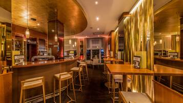 A bar area with wooden furniture, a curved ceiling, and pendant lighting.