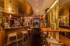 Zona de bar con mobiliario de madera, techo curvo e iluminación colgante.