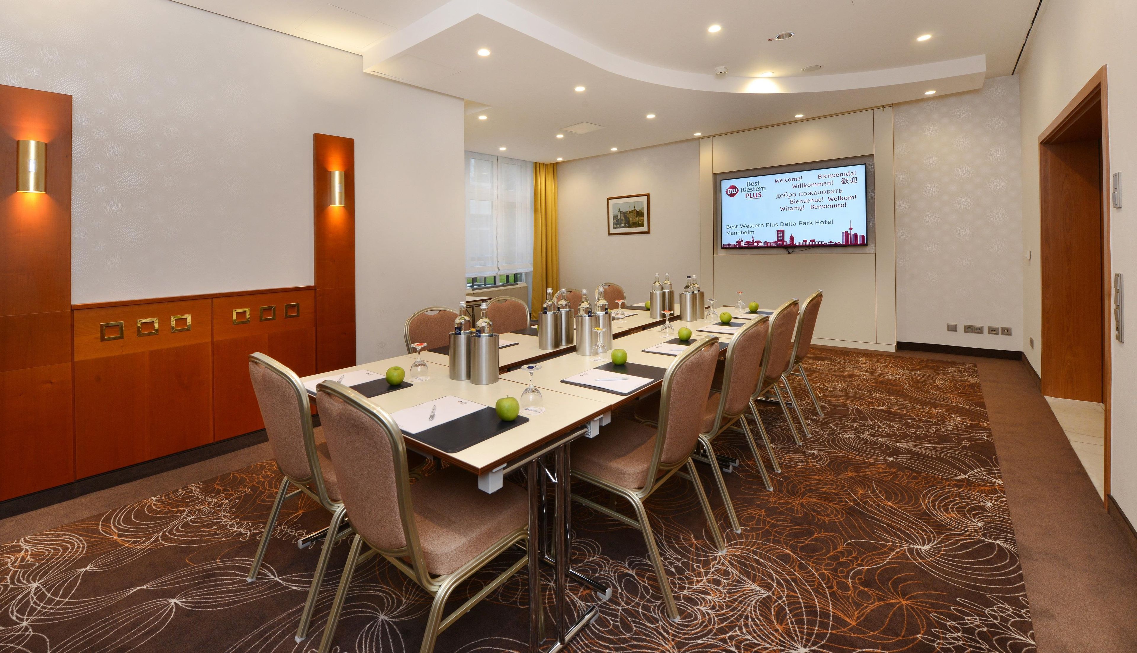 A conference room with a long table, chairs, and a screen displaying a welcome message.