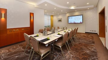 A conference room with a long table, chairs, and a screen displaying a welcome message.