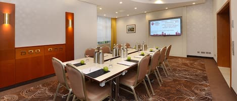 A conference room with a long table, chairs, and a screen displaying a welcome message.